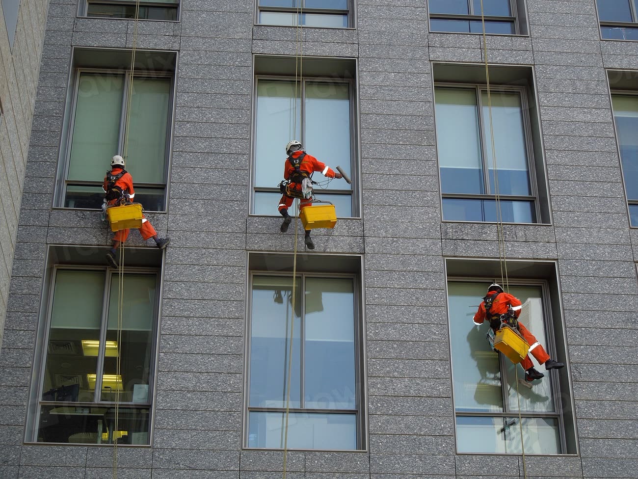 Fassadenreinigung an einem Hochhaus, ein Reinigungsteam bei der Arbeit in der Höhe